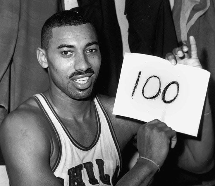 FILE - Wilt Chamberlain of the Philadelphia Warriors holds a sign in the dressing room in Hershey, Pa., after he scored 100 points as the Warriors defeated the New York Knickerbockers 169-147, March 2, 1962.
