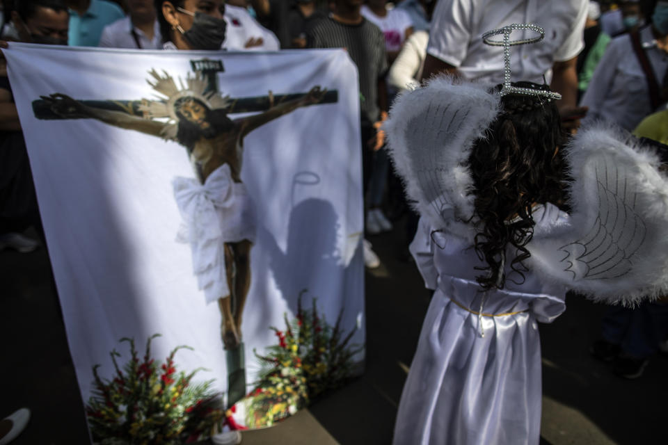 A child dressed as an angel walks past a devotee holding a religious banner depicting Jesus Christ on a cross, during an event marking Good Friday at the Metropolitan Cathedral in Managua, Nicaragua, Friday, April 7, 2023. Holy Week commemorates the last week of the earthly life of Jesus, culminating in his crucifixion on Good Friday and his resurrection on Easter Sunday. (AP Photo/Inti Ocon)