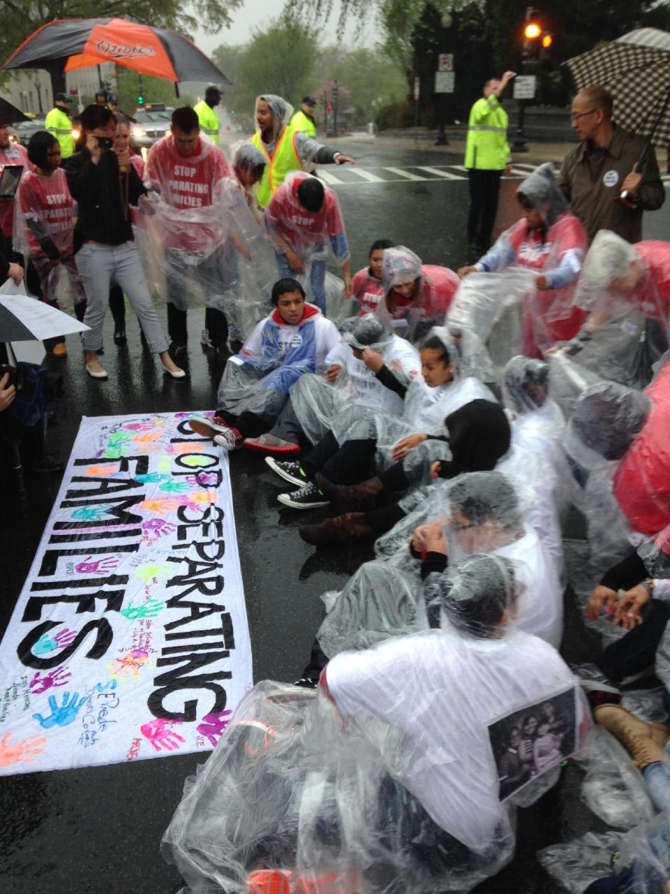 Demonstrators sit in the rain on Capitol Hill in Washington, Wednesday, April 30, 2014, during a protest calling for an end to deportations. Chanting protesters wore red shirts with the slogan “Stop Separating Families.” They locked arms and sat down in the street in the rain before Capitol Police rounded them up and loaded them in vans. (AP Photo/Luis Alonso)