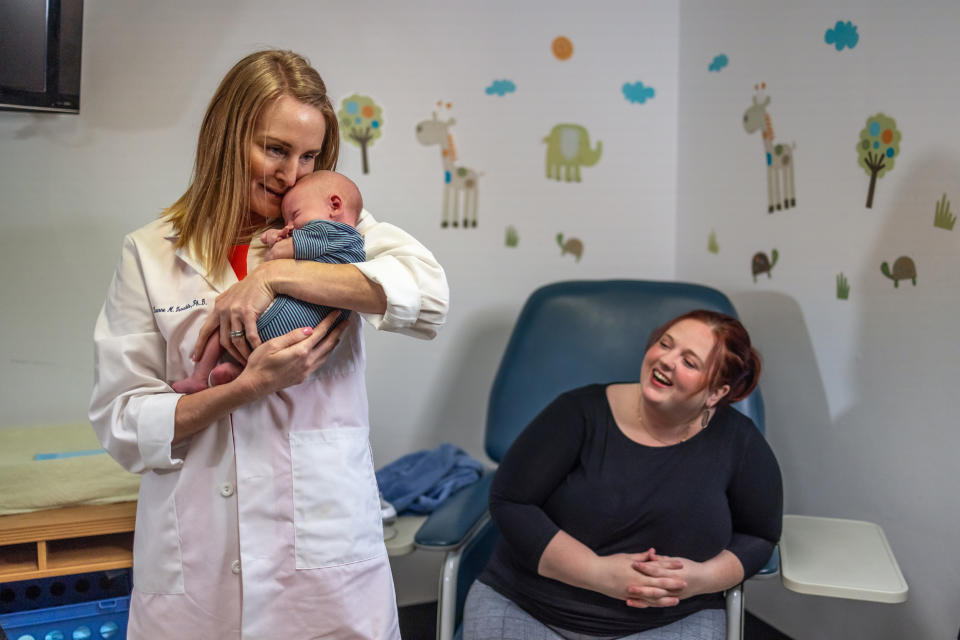 Director of the maternal and infant research lab at Pennington Biomedical Research Center Doctor Leanne Redman, left, holds Jameson, son of Julie Hardee, right, at the Pennington Biomedical Research Center at Louisiana State University in Baton Rouge on May 12, 2022. (Kathleen Flynn for NBC News)