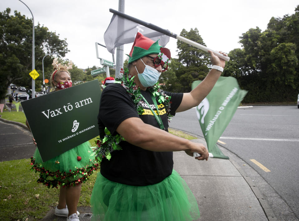 Mona Lisa, left, and Tau Apihai perform along the roadside to encourage people to get vaccinated Tuesday, Dec. 21, 2021, in Auckland, New Zealand. New Zealand will shorten the gap between second COVID-19 vaccine doses and boosters and push back the phased reopening of its borders in measures announced Tuesday to keep the omicron variant at bay. (Dean Purcell/New Zealand Herald via AP)