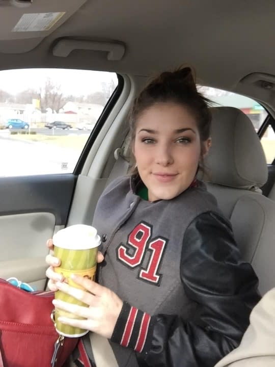 Libby Caswell holds a to-go coffee cup in a car