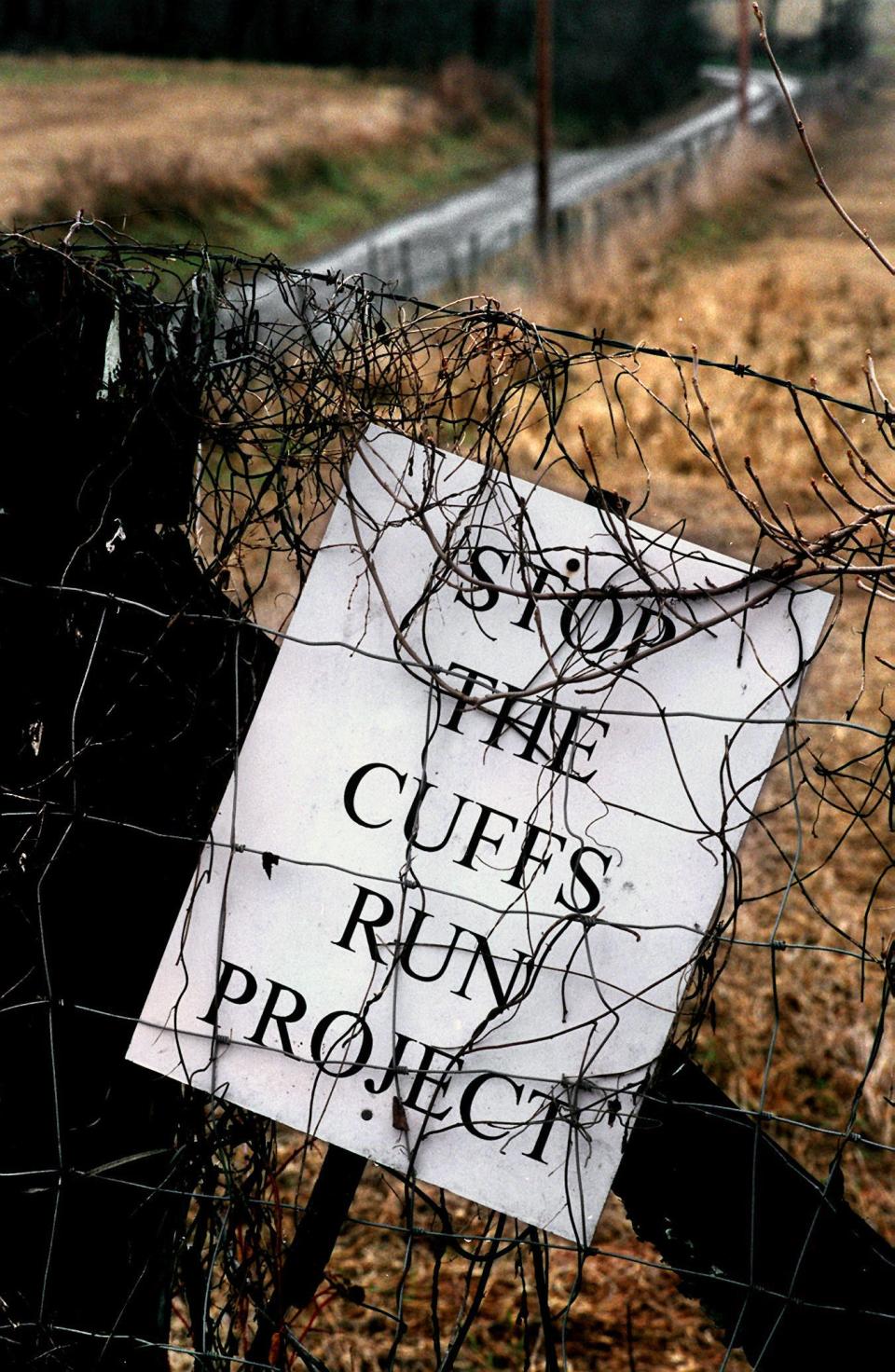 Wrapped in dormant vines, an old Cuffs Run project sign at the intersection of Old Bridgeville and Scout roads as it appeared in 1996. Opposition continued though the 1990s. The road in the background would have been under water under the proposal.