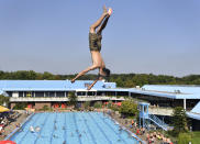 <p>Ein junger Mann hüpft in einem Schwimmbad in Gelsenkirchen von einem Sprungturm. (Bild: AP Photo/Martin Meissner) </p>