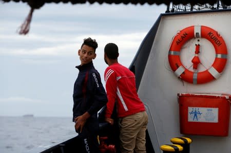 Tunisian migrants stand on the German NGO Sea-Eye migrant rescue ship 'Alan Kurdi' after they were informed they would disembark in Malta, in international waters off Malta in the central Mediterranean Sea