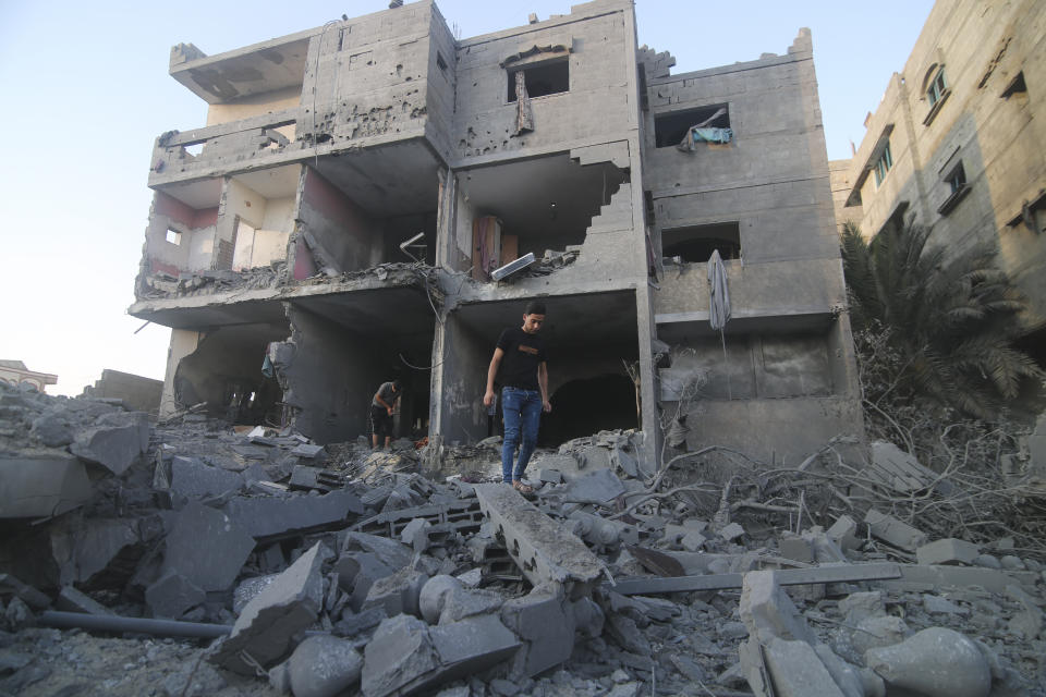 Palestinians stand by a building destroyed in an Israeli airstrike in the Rafah border, Gaza Strip, on Monday, Oct. 16, 2023. (AP Photo/Hatem Ali)