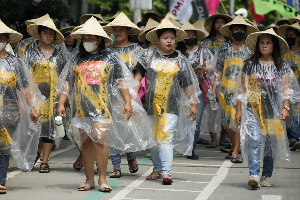 Un grupo de personas, cubiertas con ponchos de plástico, participan en un acto que forma parte de la marcha global contra los combustibles fósiles, el 15 de septiembre de 2023, en la ciudad de Quezon, Filipinas. (AP Foto/Aaron Favila)