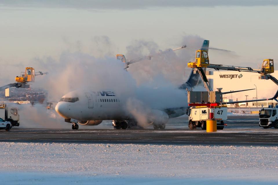 A de-icing station sprays a WestJet Airlines Boeing 737 jetliner prior to its departure at the international airport in Calgary. Temperatures on Saturday morning have rendered de-icing fluid ineffective across most of the Prairies. (Larry MacDougal/The Canadian Press - image credit)