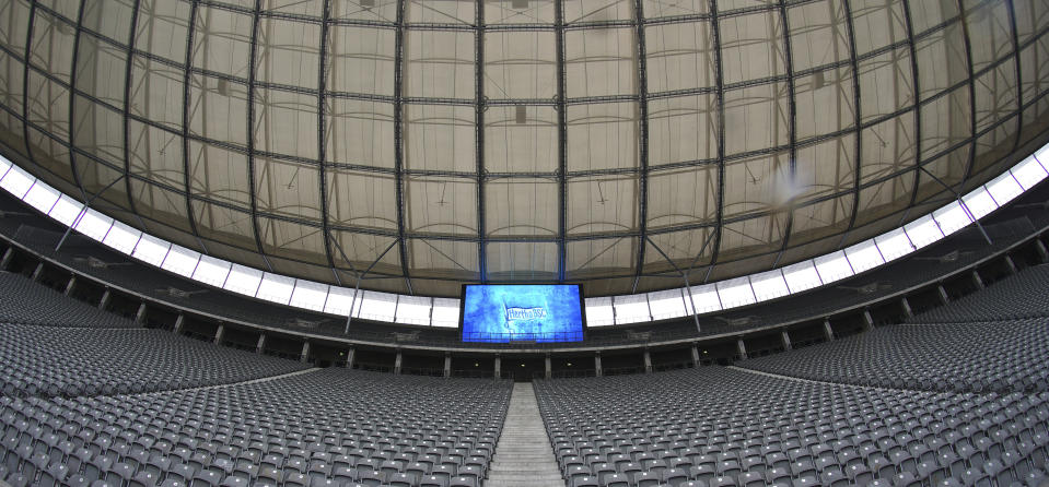 In this photo taken on Saturday, June 20, 2020, the flag of Hertha BSC is displayed on a giant video screen above empty spectator seats during a German Bundesliga soccer match between Hertha BSC Berlin and Bayer Leverkusen in Berlin, Germany. (AP Photo/Michael Sohn, Pool)