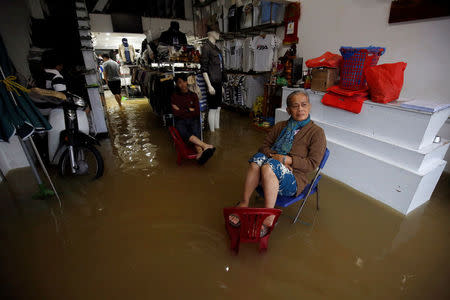 Residents sit on their flooded fashion shop after typhoon Damrey hits Vietnam in Hue city, Vietnam November 5, 2017. REUTERS/Kham