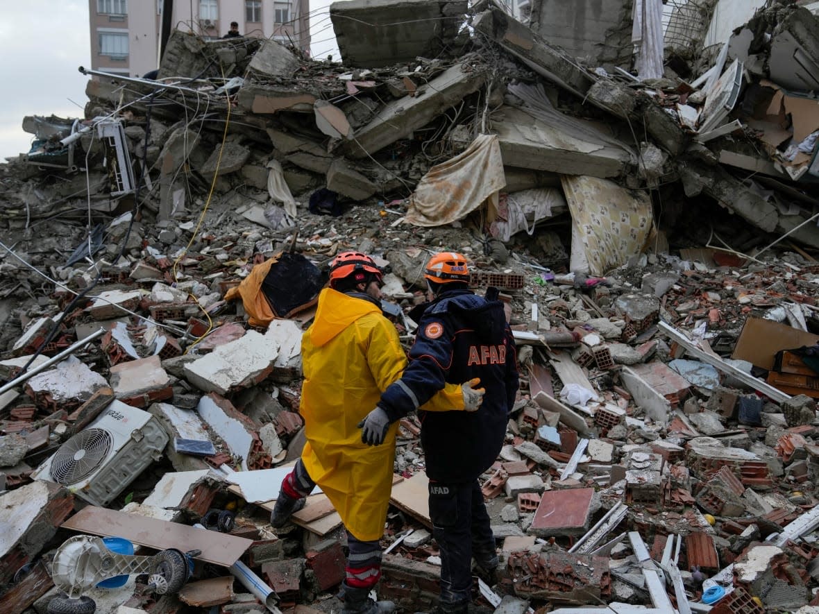 Emergency team members pause for a moment as they search for people in a destroyed building in Adana, Turkey, on Monday. (Khalil Hamra/The Associated Press - image credit)