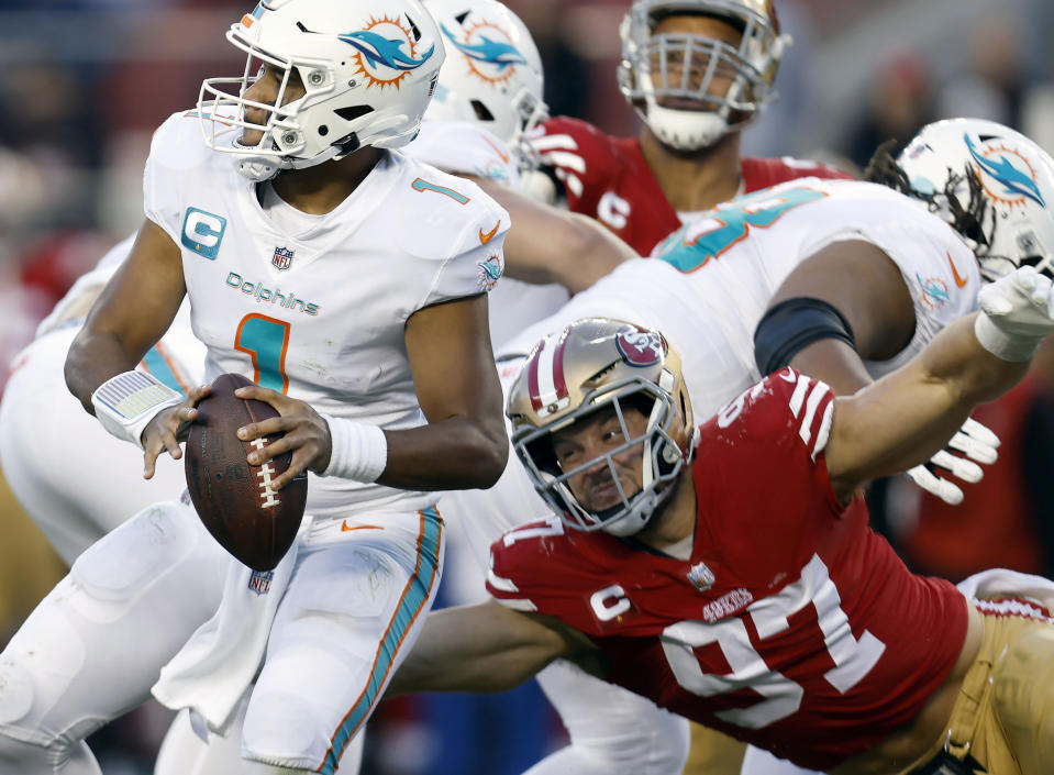 FILE - Miami Dolphins quarterback Tua Tagovailoa (1) looks to pass before San Francisco 49ers defensive end Nick Bosa (97) caused him to fumble which 49ers linebacker Dre Greenlaw returned for a touchdown during the second half of an NFL football game in Santa Clara, Calif., Dec. 4, 2022. The 49ers are still waiting for Bosa to arrive in camp with less than three weeks before the start of the season. (AP Photo/Jed Jacobsohn, File)