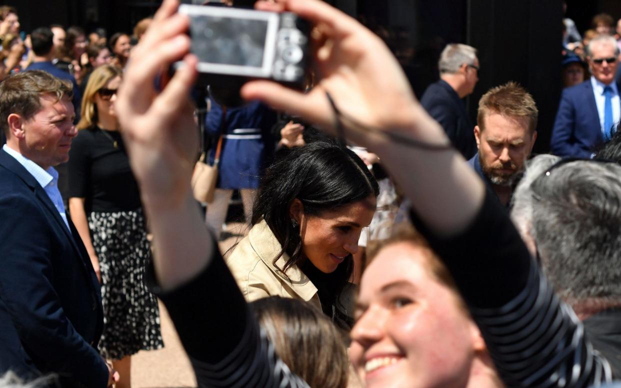 The Duchess of Sussex (centre) has warned of the dangers of Instagram-filtered life, saying it skews young people's 'sense of self worth' - AFP
