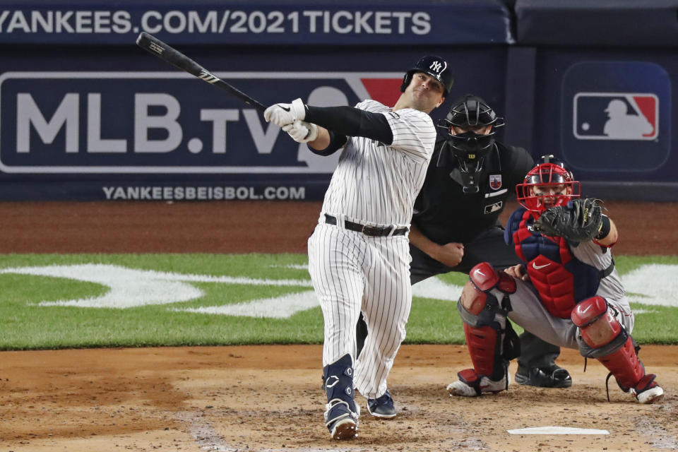 New York Yankees Mike Ford, left, follows through on a two-run home run during the third inning of a baseball game against the Boston Red Sox, Sunday, Aug. 16, 2020, in New York. Red sox catcher Kevin Plawecki, right, and home plate umpire Ryan Additon, center, watch. (AP Photo/Kathy Willens)