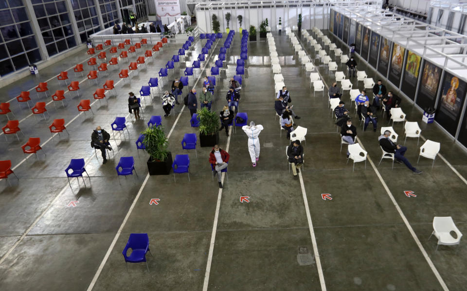 People sit, after receiving a COVID-19 vaccine at Belgrade Fair makeshift vaccination center, in Belgrade, Serbia, Monday, Jan. 25, 2021. Serbia were the first European country to receive the Chinese Sinopharm's vaccine for mass inoculation programmes. (AP Photo/Darko Vojinovic)