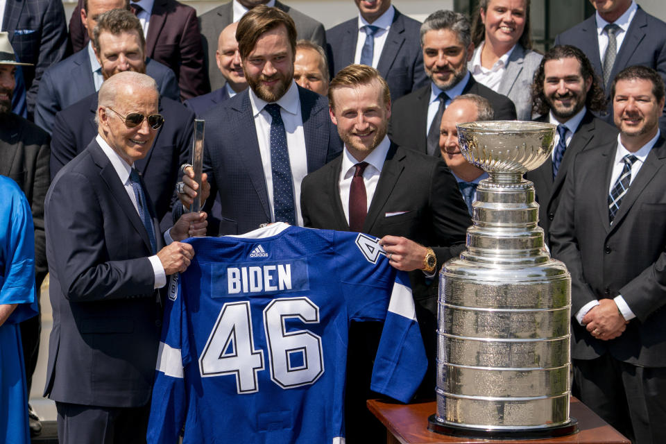 From left, President Joe Biden poses in front of the Stanley Cup with Tampa Bay Lightning alternative captain Victor Hedman and captain Steven Stamkos and other members of the team as he is given a team jersey and a ceremonial hockey stick during an event to celebrate the Tampa Bay Lightning's 2020 and 2021 Stanley Cup championships at the White House in Washington, Monday, April 25, 2022. (AP Photo/Andrew Harnik)