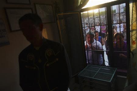 Friends and neighbours of inmate Edgar Tamayo peer inside the window of the Tamayo family house in Miacatlan, Morelos state January 22, 2014. REUTERS/Edgard Garrido