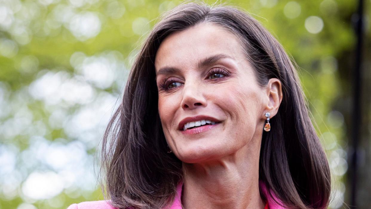 Queen Letizia smiling in red dress and pink coat