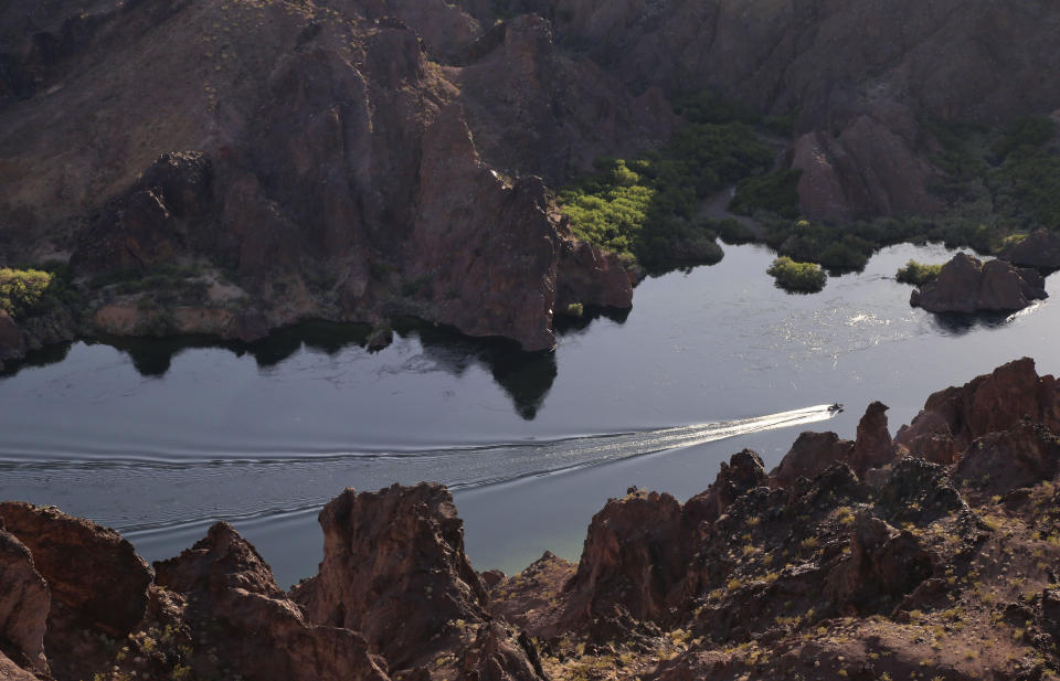 FILE - In this April 12, 2013, file photo, a patrol boat makes its way upstream along the Colorado River in Black Canyon just south of Hoover Dam near Willow Beach, Ariz. The Colorado River Indian Tribes Water Resources has played an outsized role in Arizona to help keep Lake Mead from falling to drastically low levels. Still, Arizona is expected to face the first-ever mandatory cuts to its Colorado River water supply in 2022. (AP Photo/Julie Jacobson, File)