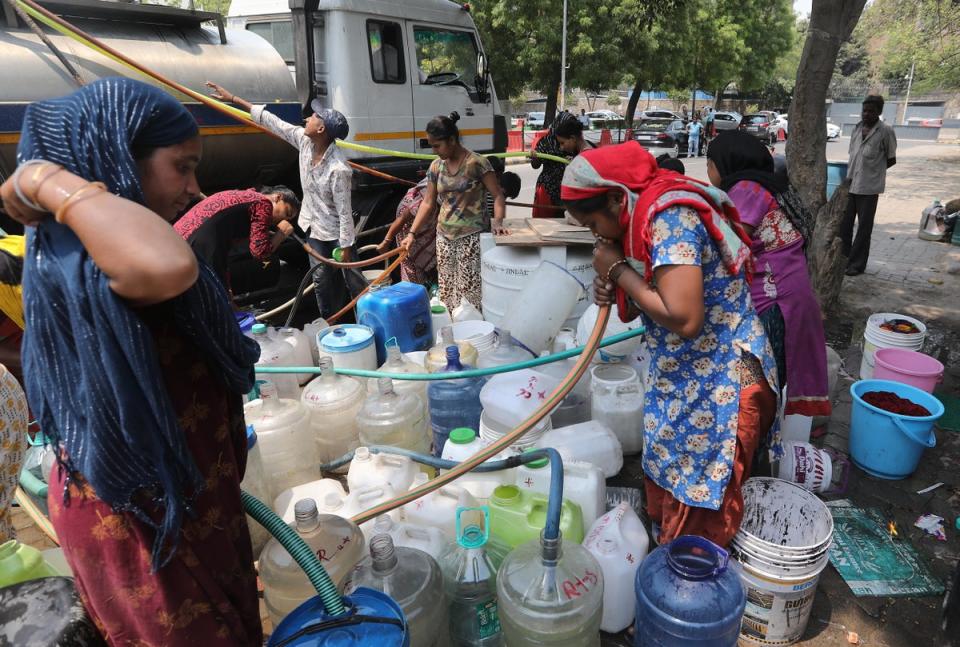 People fill up canisters and containers with water from a tanker at a makeshift settlement in Chankyapuri in New Delhi (EPA)