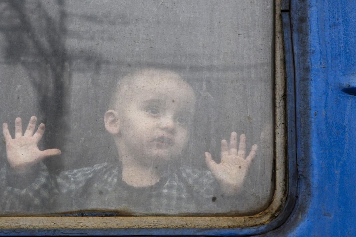 A child watches from from a train carriage waiting to leave Ukraine for western Ukraine at the railway station in Kramatorsk, eastern Ukraine, Sunday, Feb. 27, 2022. The U.N. refugee agency says nearly 120,000 people have so far fled Ukraine into neighboring countries in the wake of the Russian invasion. The number was going up fast as Ukrainians grabbed their belongings and rushed to escape from a deadly Russian onslaught.