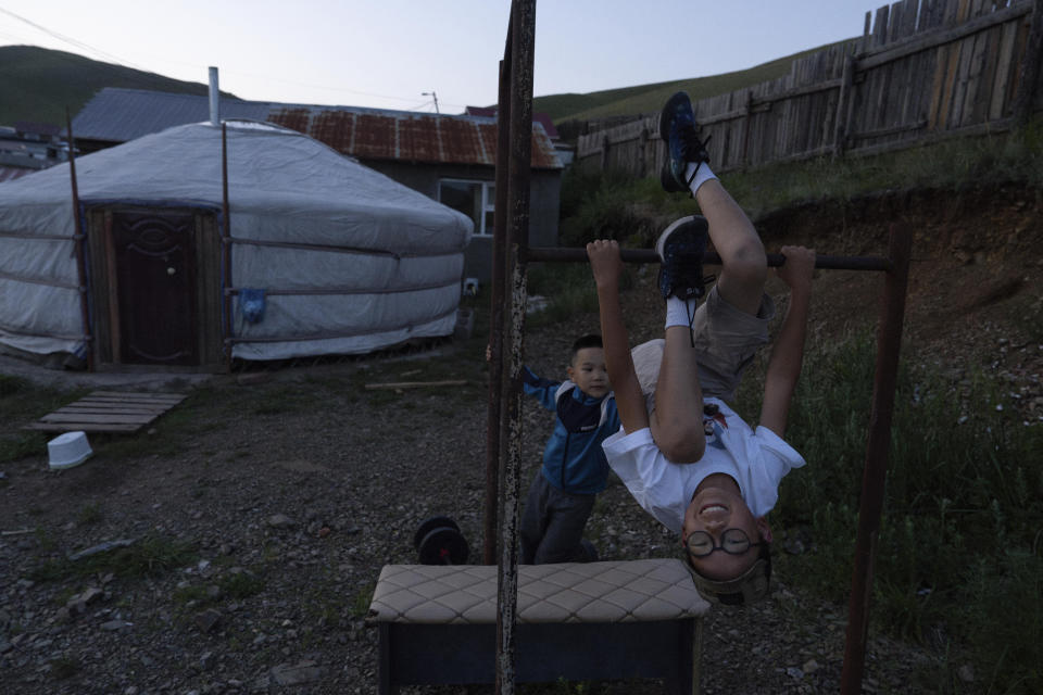 Twelve-year-old Gerelt-Od Kherlen, foreground, plays on pull up bar with his younger brother Gerelt-Ireedui Kherlen at their home in a Ger district on the outskirts of Ulaanbaatar, Mongolia, Tuesday, July 2, 2024. Growing up in a Ger district without proper running water, Gerelt-Od fetched water from a nearby kiosk every day for his family. Carrying water and playing ball with his siblings and other children made him strong and resilient. (AP Photo/Ng Han Guan)