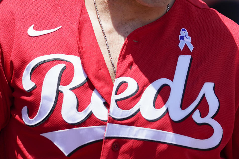 A powder-blue ribbon is displayed on the uniform of Cincinnati Reds first baseman Joey Votto in honor of Father's Day during a baseball game against the Milwaukee Brewers, Sunday, June 19, 2022, in Cincinnati. (AP Photo/Jeff Dean)