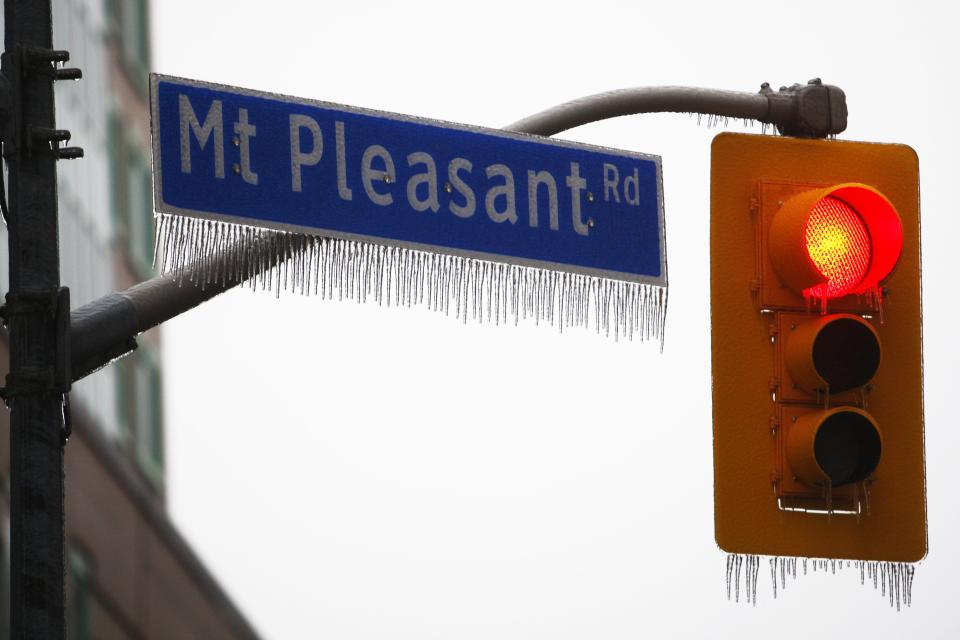 Icicles hang from a signal light and a street sign after freezing rain in Toronto, Ontario December 22, 2013. Thousands of households are without power in the Greater Toronto area following an overnight ice storm. REUTERS/Hyungwon Kang (CANADA - Tags: ENVIRONMENT)