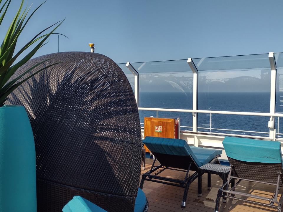 An outdoor deck on Carnival cruise with sunbeds facing toward the side of the ship.