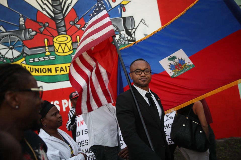 <p>Fandzy Bernadin holds an American flag as he joins with others to mark the 8th anniversary of the massive earthquake in Haiti and to condemn President Donald Trump’s reported statement about immigrants from Haiti, Africa and El Salvador on Jan. 12, 2018 in Miami, Fla. (Photo: Joe Raedle/Getty Images) </p>