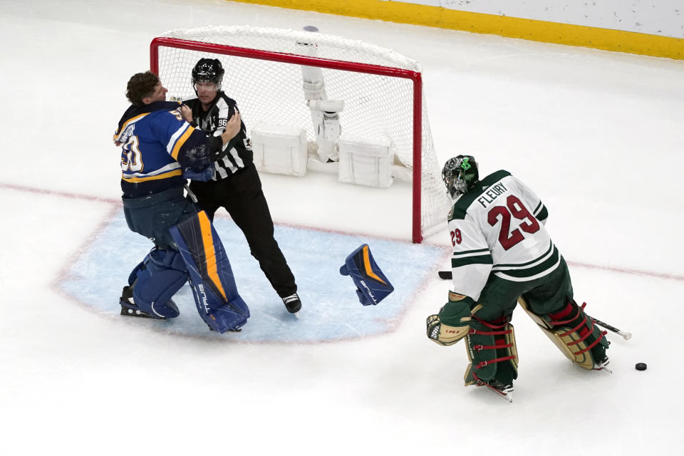 FILE - St. Louis Blues goaltender Jordan Binnington, left, is held back from fighting Minnesota Wild goaltender Marc-Andre Fleury (29) by linesman David Brisebois, center, during the second period of an NHL hockey game March 15, 2023, in St. Louis. The league rule changes have made it so punitive that goalie fighting has essentially disappeared from the highest level of hockey. (AP Photo/Jeff Roberson, File)