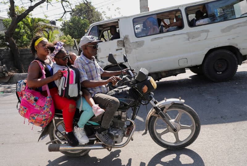 Un hombre conduce una motocicleta con personas y sus pertenencias por una calle en Puerto Príncipe