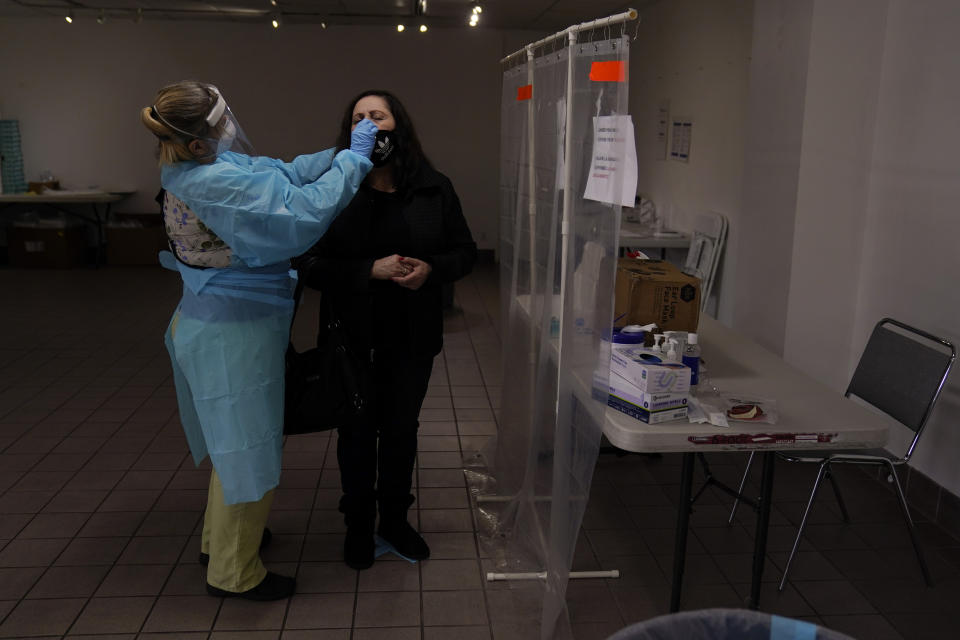 FILE - In this Dec. 27, 2020, file photo, registered nurse Leslie Clark, left, collects a nasal swab sample from a woman who declined to give her name at a COVID-19 testing site in Los Angeles. Coronavirus hospitalizations are falling across the United States, but deaths have remained stubbornly high. (AP Photo/Jae C. Hong, File)