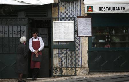 A waiter speaks with a woman as he awaits customers at a restaurant in downtown Lisbon November 26, 2012. REUTERS/Rafael Marchante