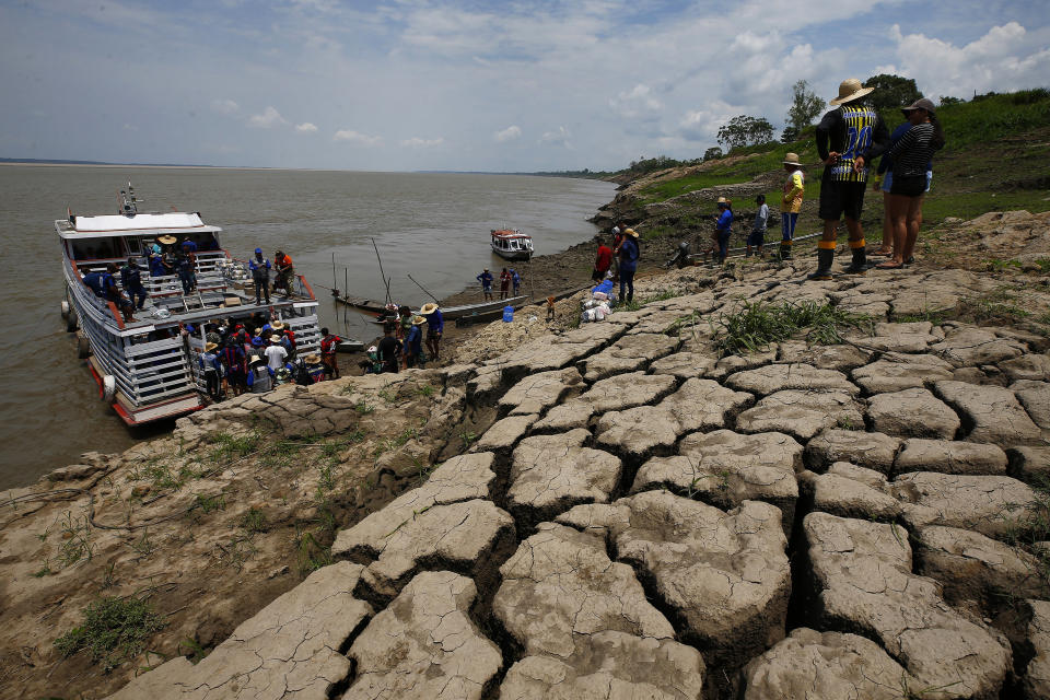 FILE - Residents of a riverside community carry food and containers of drinking water after receiving aid due to the ongoing drought in Careiro da Varzea, Amazonas state, Brazil, Tuesday, Oct. 24, 2023. On Tuesday, the municipality distributed emergency kits using an improvised barge originally designed to transport cattle. (AP Photo/Edmar Barros, File)