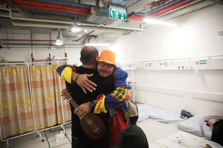 An Israeli medical clown hugs with a Syrian man who crossed the armistice line from Syria to the Israeli-occupied Golan Heights to help sick people get medical treatment in Israel, July 11, 2018. REUTERS/ Ronen Zvulun