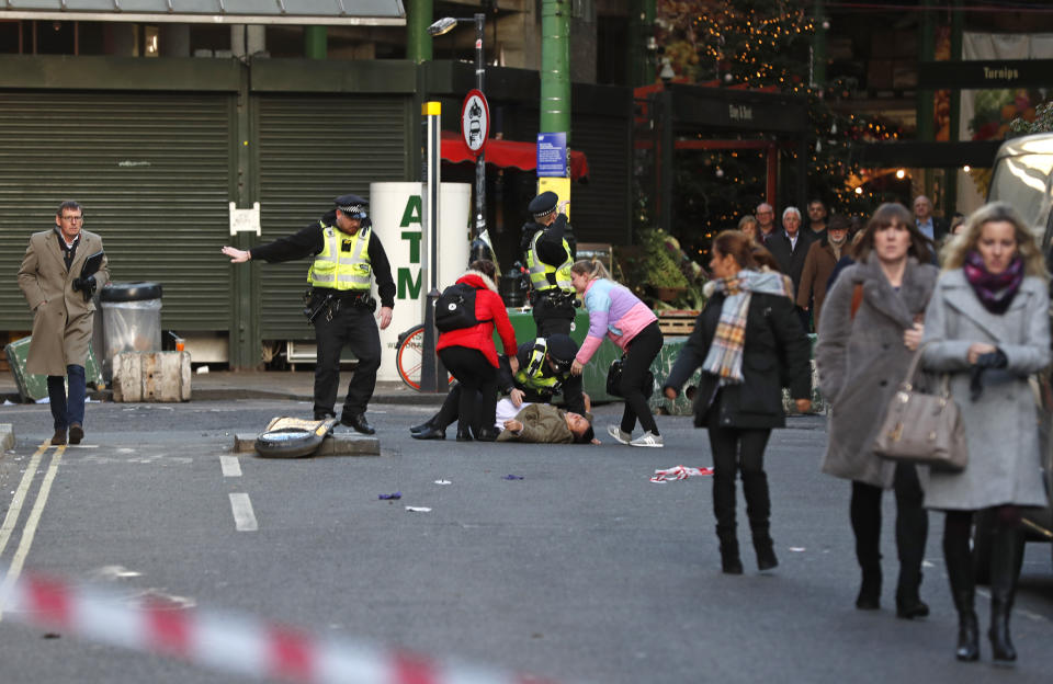 A person is assisted after falling when Police evacuated people from Borough Market on the south side of London Bridge in London, Friday, Nov. 29, 2019. British police say several people have stabbed near to London Bridge, and a man has been detained. The news came after witnesses reported hearing gunshots in the area. (AP Photo/Frank Augstein)