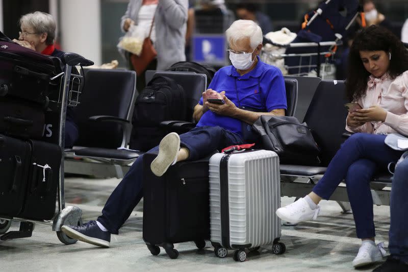 A traveller wearing protective face mask as a precautionary measure types on his phone, after the second case of coronavirus in Sao Paulo was confirmed, at Guarulhos International Airport in Guarulhos