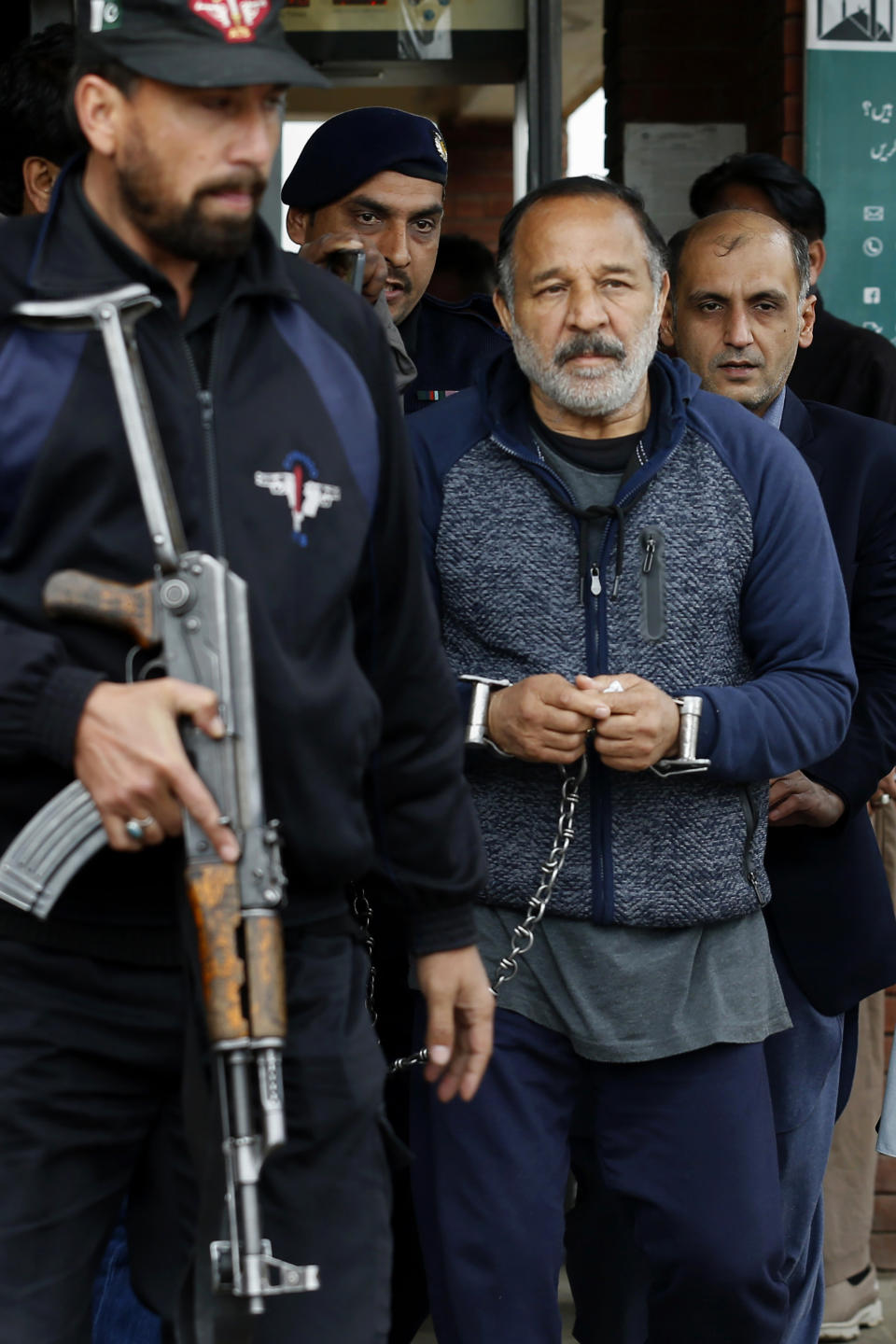 Pakistani police officers escort to Piran Ditta Khan, center, who has been arrested in the killing of a British woman police officer, following his court appearance in Islamabad, Pakistan, Wednesday, Jan. 29, 2020. Khan, who was taken in custody earlier this week, appeared before a court in Islamabad over an extradition request from Britain. His arrests was the result of close cooperation between Pakistani authorities and British detectives, police said. Khan was remanded in custody and is due back in court mid in January. (AP Photo/Anjum Naveed)