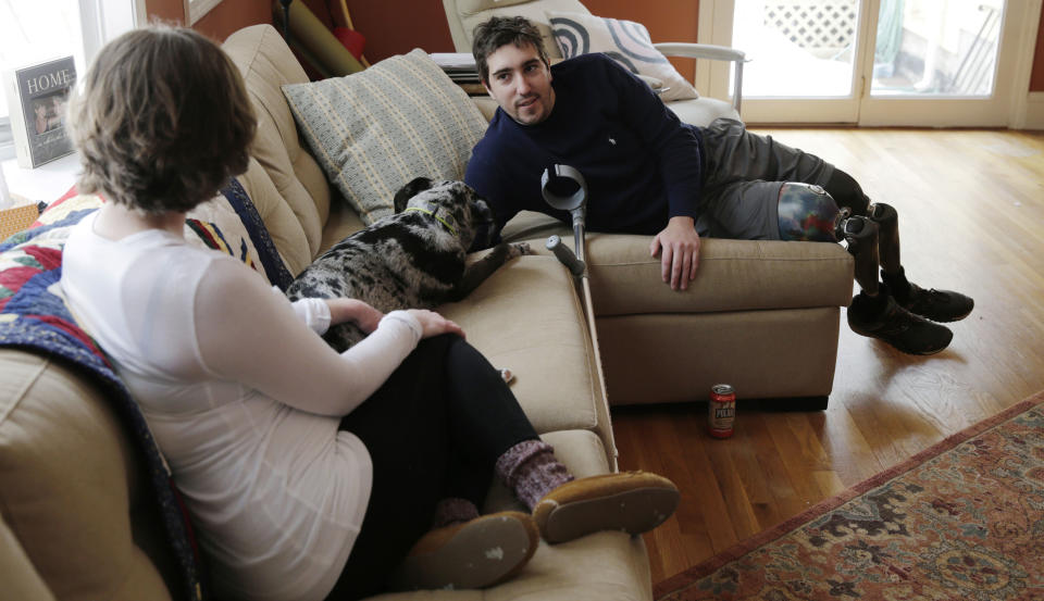 ADVANCE FOR WEEKEND USE APRIL 4-5 -- In this March 14, 2014 photo, Jeff Bauman, who lost both his legs above the knee in the Boston Marathon bombing, relaxes on the couch with his fiancee Erin Hurley and dog Bandit, at their Carlisle, Mass., home. The couple are expecting their first child in July. (AP Photo/Charles Krupa)