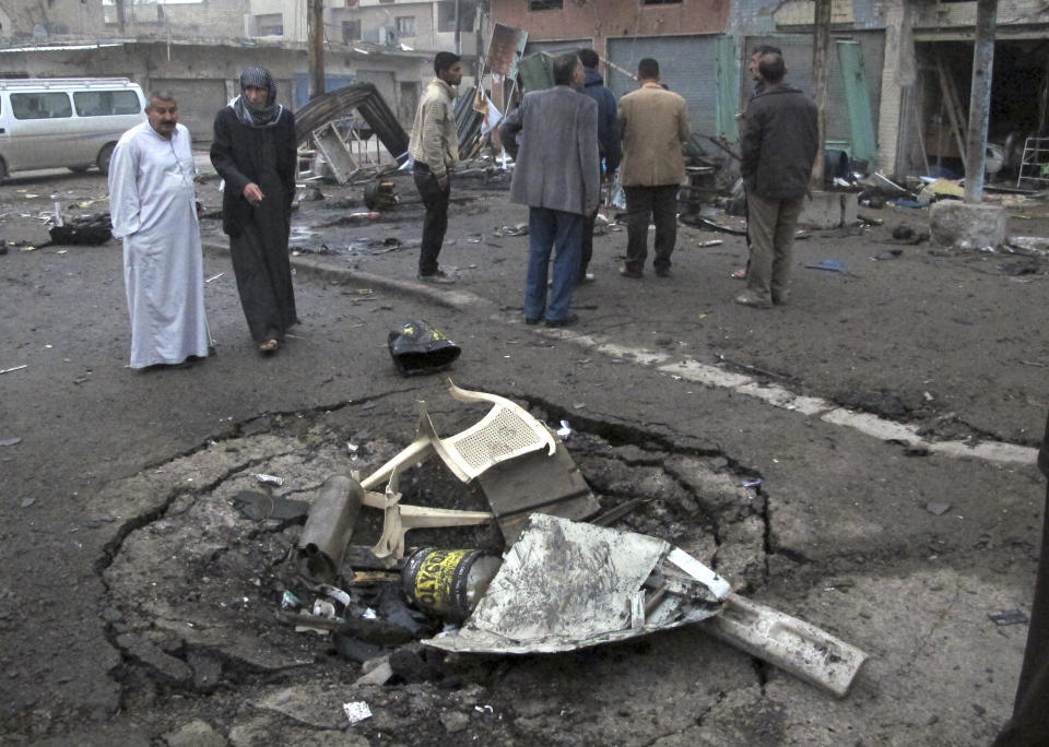 Iraqi civilians inspect a crater caused by a car bomb explosion at a commercial street in al-Ameen district in southeastern Baghdad, Iraq, Sunday, March 16, 2014. A series of car bomb attacks targeting commercial areas and a restaurant killed and wound scores of people, Saturday in Iraq's capital, Baghdad, authorities said. (AP Photo/Khalid Mohammed)