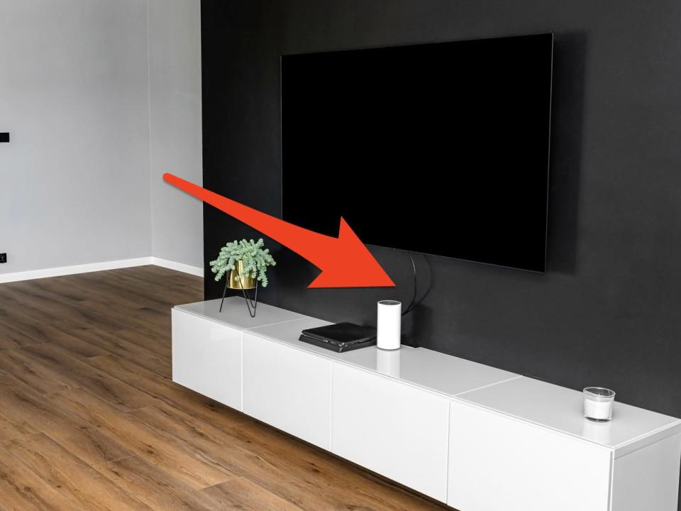 TV mounted on a dark-gray wall with dangling wires below and a red arrow pointing to wires