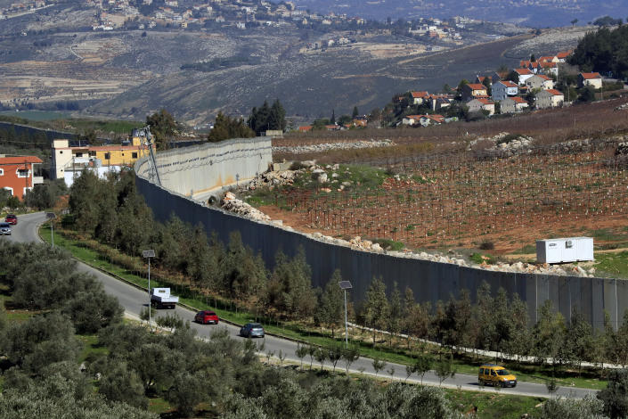 Cars drive next to the wall that separates Lebanon from Israel in the southeastern Lebanese village of Kfar Kila, Saturday, Jan. 21, 2023. Green Without Borders that is active in southern Lebanon, including areas along the border with Israel, is being blamed by Israel, the U.S. and some in Lebanon for being an arm for Hezbollah to cover some of the group's military activities. The association denies such charges. (AP Photo/Mohammed Zaatari)