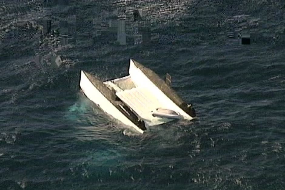 A catamaran is overturned in the water off Stockton Beach, Newcastle.