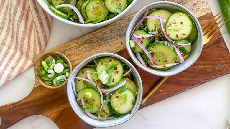 Cucumber salad in bowls on cutting board