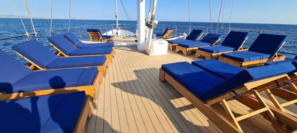 blue lounge chairs on a wooden deck on a boat