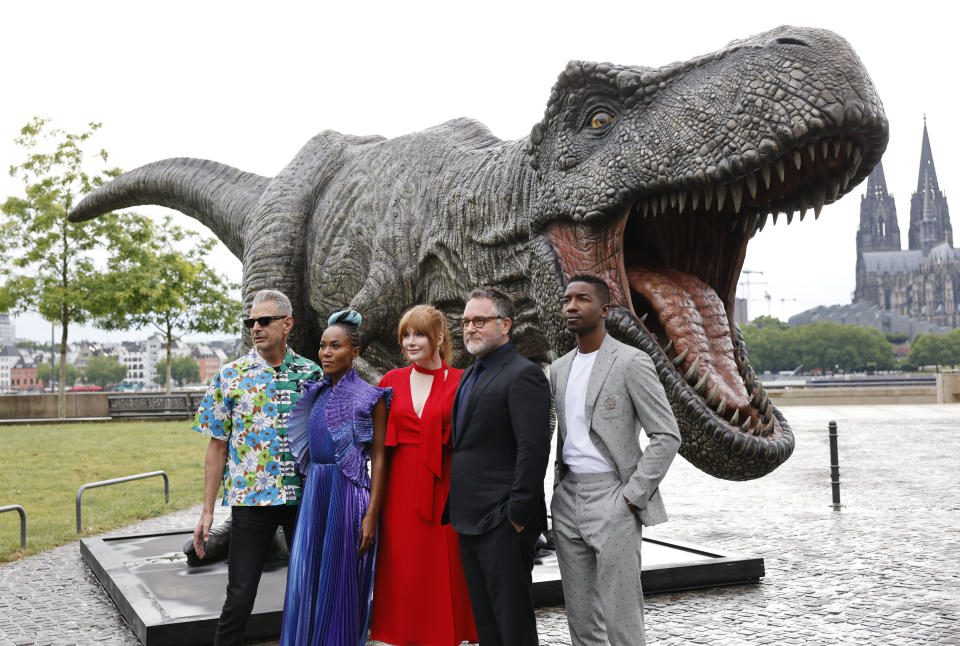 Actors from left, Jeff Goldblum, DeWanda Wise, Bryce Dallas Howard, director Colin Trevorrow and actor Mamoudou Athie stand in front of a T-Rex figure, during a photocall for the new film - Jurassic World Dominion, in Cologne, Germany, Sunday, May 29, 2022. (Thomas Banneyer/dpa via AP)