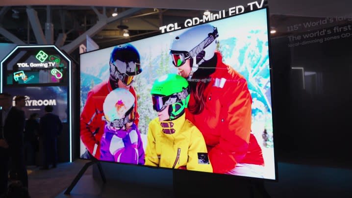 A family of skiers in brightly-colored gear shown on a TCL 115-inch TV.