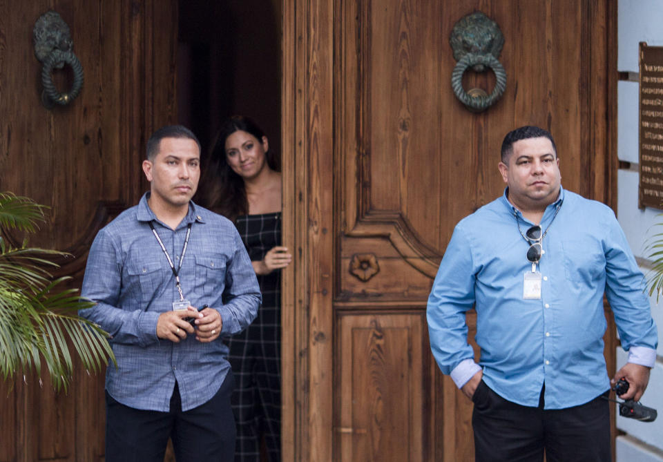 Puerto Rico's first lady Beatriz Rossello opens La Fortaleza Main Gate to let her dogs out, as two security men stand guard at La Fortaleza, the Governor's Mansion in San Juan, Puerto Rico, Wednesday, July 24, 2019. Protesters are demanding that Gov. Ricardo Rossello step down for his involvement in a private chat in which he used profanities to describe an ex-New York City councilwoman and a federal control board overseeing the island's finance. (AP Photo/Dennis M. Rivera Pichardo)