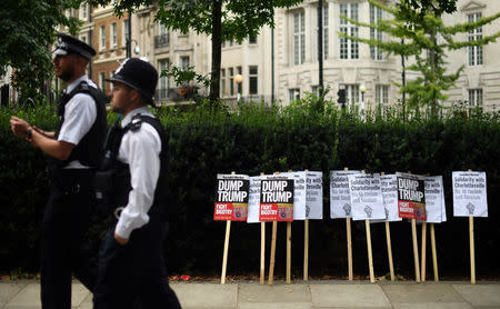 Police officers walk past placards during an anti-fascist protest outside the U.S Embassy in London, Britain, August 14, 2017. REUTERS/Hannah McKay